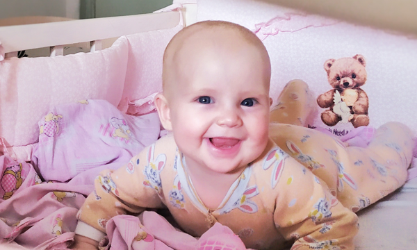 Ein lachendes Baby schaut Dich an.